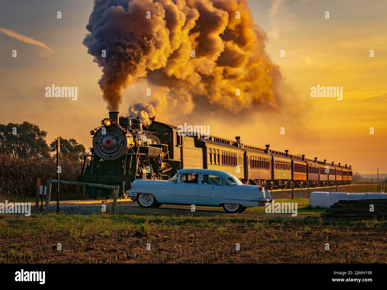 Treno passeggeri a vapore antico che si avvicina all'alba con un pieno di vapore e fumo Foto Stock