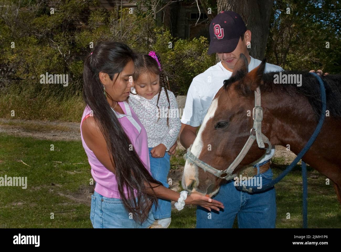 Famiglia nativa americana di genitori e figlia che nutrono una carota al loro cavallo da compagnia, Fort Hall Idaho (Shoshone Bannock) Foto Stock