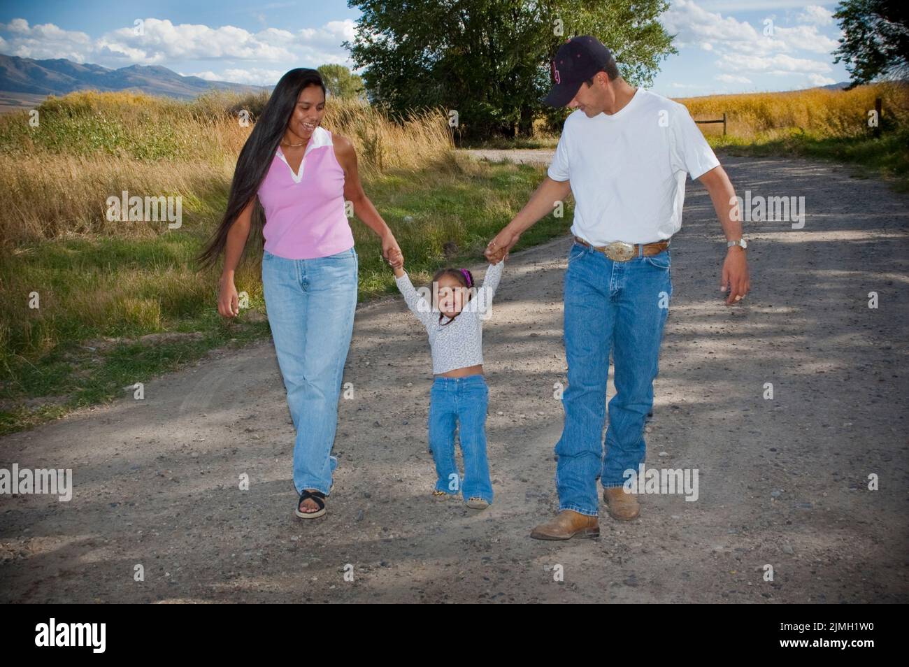 I genitori di Shoshone Bannock camminano lungo una strada di campagna con una figlia giovane mano in mano, Fort Hall Idaho Foto Stock