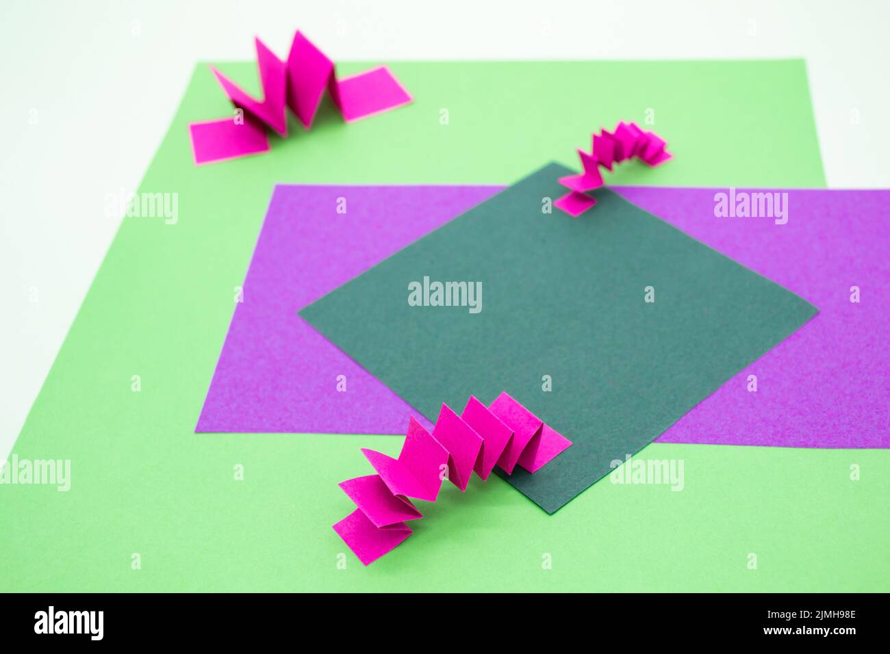 Sfondo astratto in verde, rosa e viola con 3D elementi in carta, motivo a zig zag . Come sfondo per i prodotti pubblicitari, spazio copia. Foto Stock