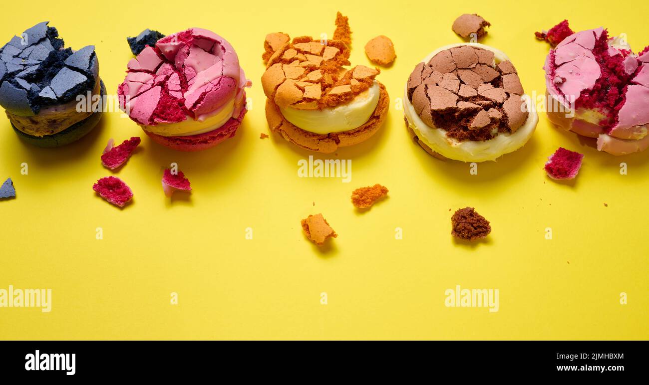 Macaroni rotondi spezzati con briciole su sfondo giallo, dessert delizioso, vista dall'alto Foto Stock