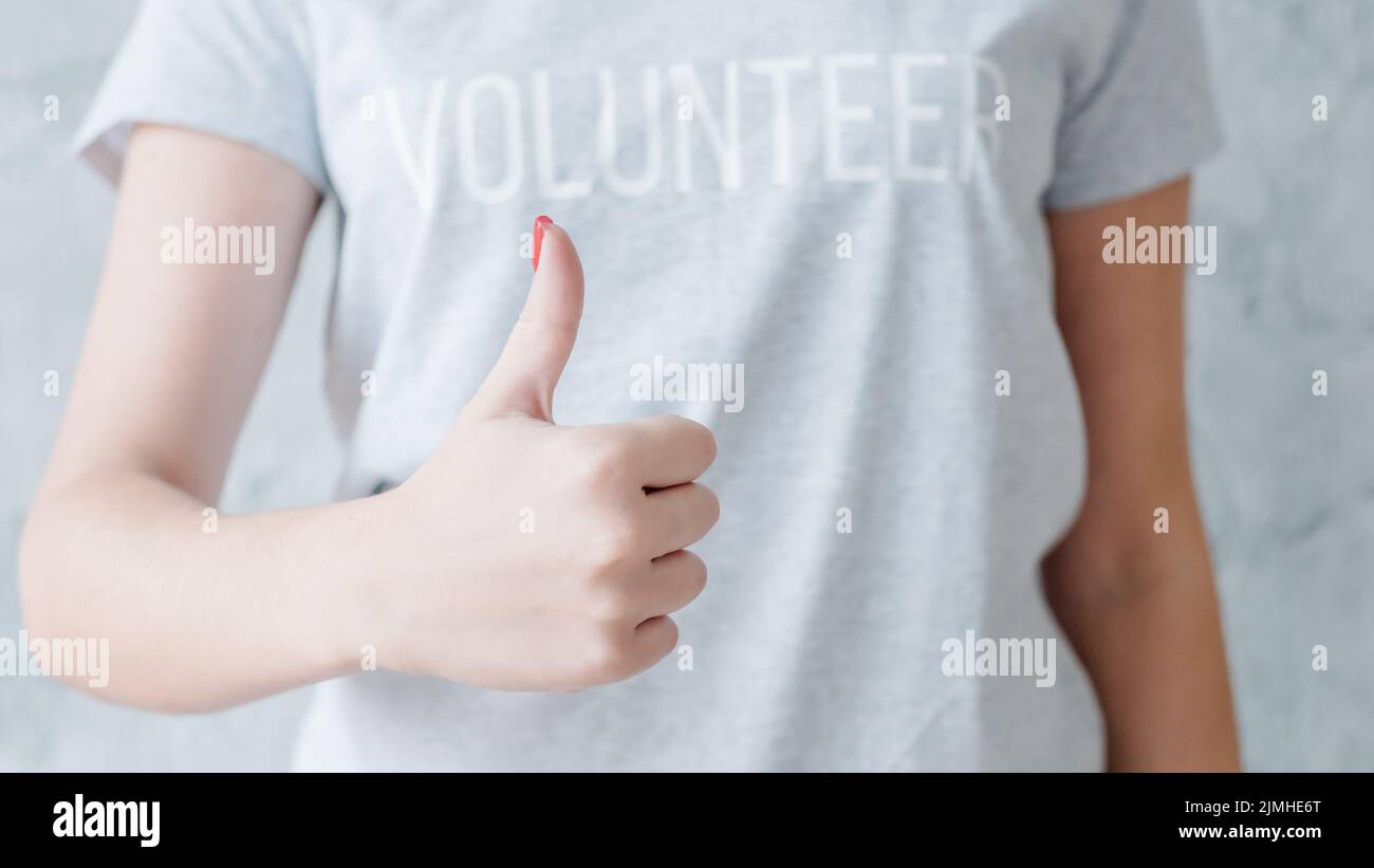 programma di carità volontario femminile mostrando pollice in su Foto Stock