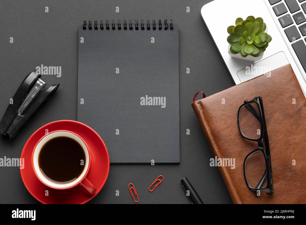 Disposizione elementi ufficio sfondo scuro con blocco note Foto Stock