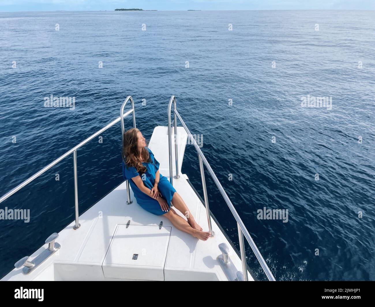 Giovane donna seduta su un prua yacht godendo viaggio su un oceano Foto Stock