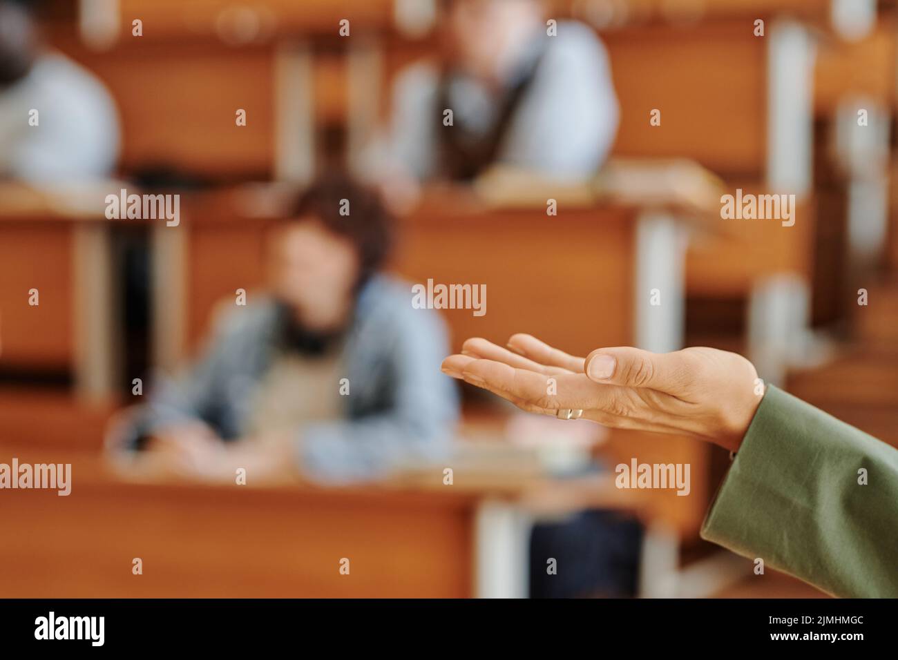 Mano dell'insegnante dell'università o dell'università che si levano in piedi davanti al pubblico e che fa il discorso circa l'argomento principale della lezione o del seminario Foto Stock
