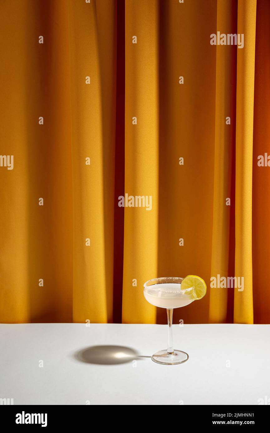 Piatto da cocktail di lime tavolo bianco contro tenda gialla Foto Stock