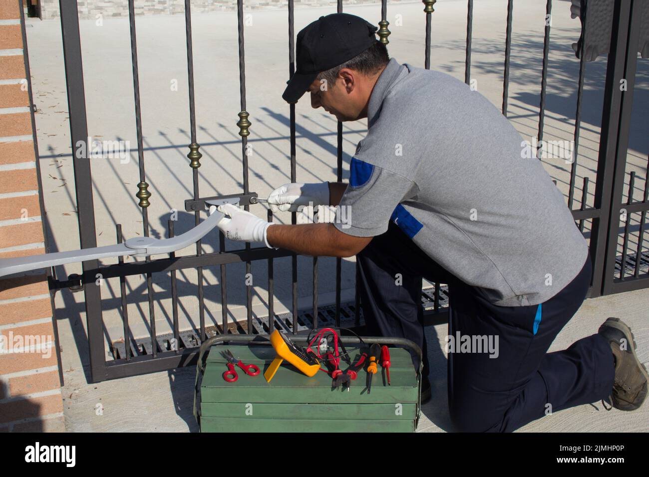 Elettricista al lavoro con utensili del settore durante l'assemblaggio e la riparazione del motore di un cancello automatico. Faccia esso voi stessi il lavoro Foto Stock