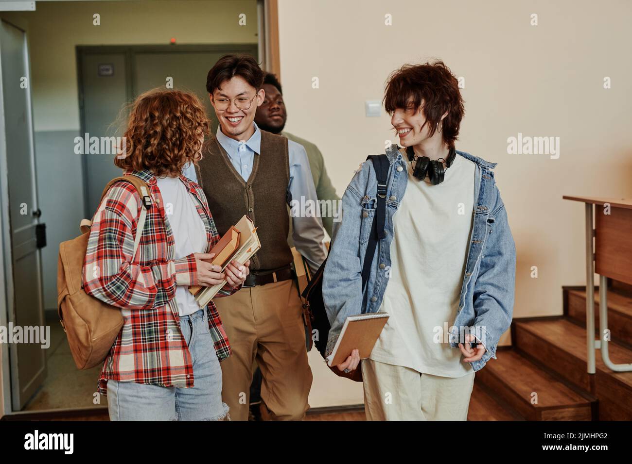 Happy highSchool adolescenti studenti in casualwear discutere di notizie mentre si entra in sala conferenze al mattino o dopo la pausa Foto Stock