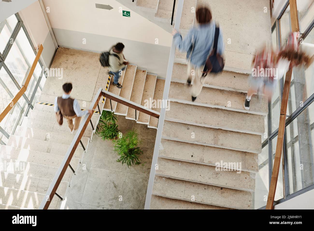 Movimento blurry di teenage multiculturale maschi e femmine studenti di scuola superiore su scale all'interno della grande università moderna Foto Stock