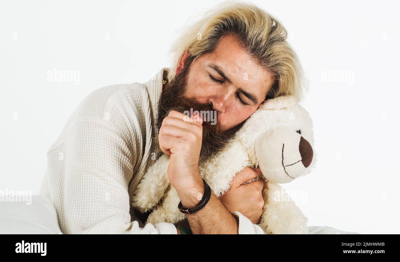 L'uomo dorme con l'orsacchiotto in camera da letto. Ragazzo bearded abbraccio morbido giocattolo rilassarsi a letto. Sogni dolci. Foto Stock