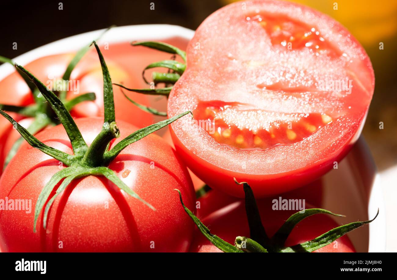 Pomodori maturi isolati. Verdure rosse in primo piano. Pomodori maturi dall'aspetto gustoso con gambi verdi. Foto Stock