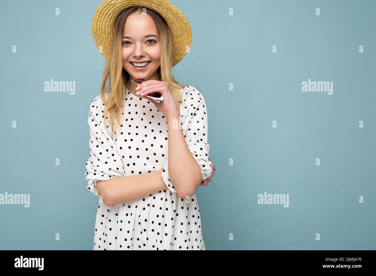 Giovane bella donna. Donna alla moda in abito estivo casual e cappello di paglia. La femmina positiva mostra emozioni facciali. Divertente modello iso Foto Stock