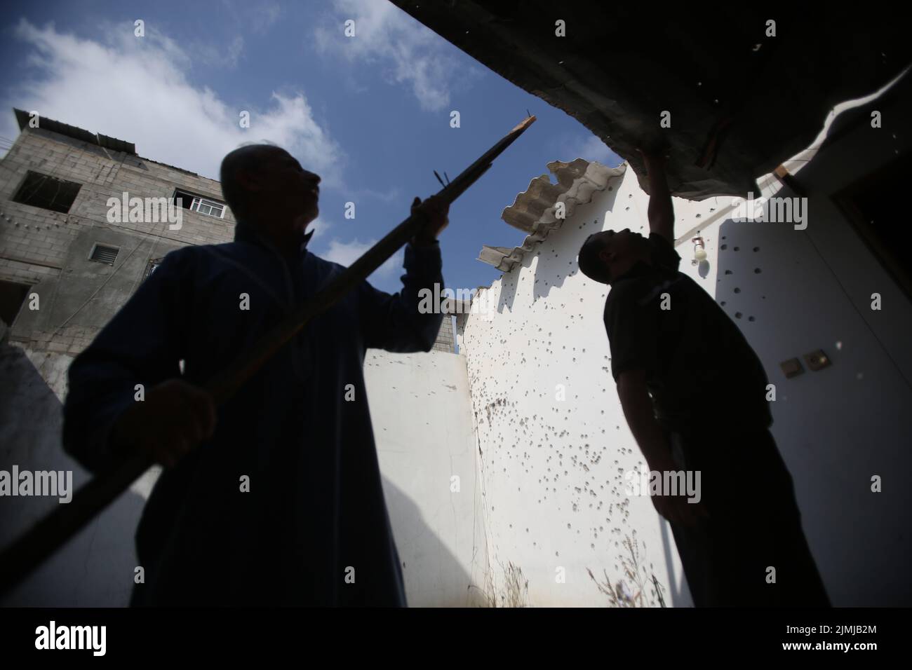 Gaza, Palestina. 06th ago 2022. I palestinesi ispezionano un muro pieno di buchi dallo shrapnel di un missile israeliano che ha colpito una casa palestinese nel campo profughi di Jabalya nella striscia settentrionale di Gaza. Almeno 15 persone sono morte e 140 sono state ferite, compreso un bambino, in una serie di attacchi aerei israeliani contro diversi bersagli nella striscia di Gaza, compreso un appartamento residenziale nel quartiere di al-Rimal. Le Brigate al-Quds, l'ala armata della Jihad islamica palestinese, hanno annunciato che il leader senior Tayseer al-Jabari è stato ucciso negli attacchi. Credit: SOPA Images Limited/Alamy Live News Foto Stock