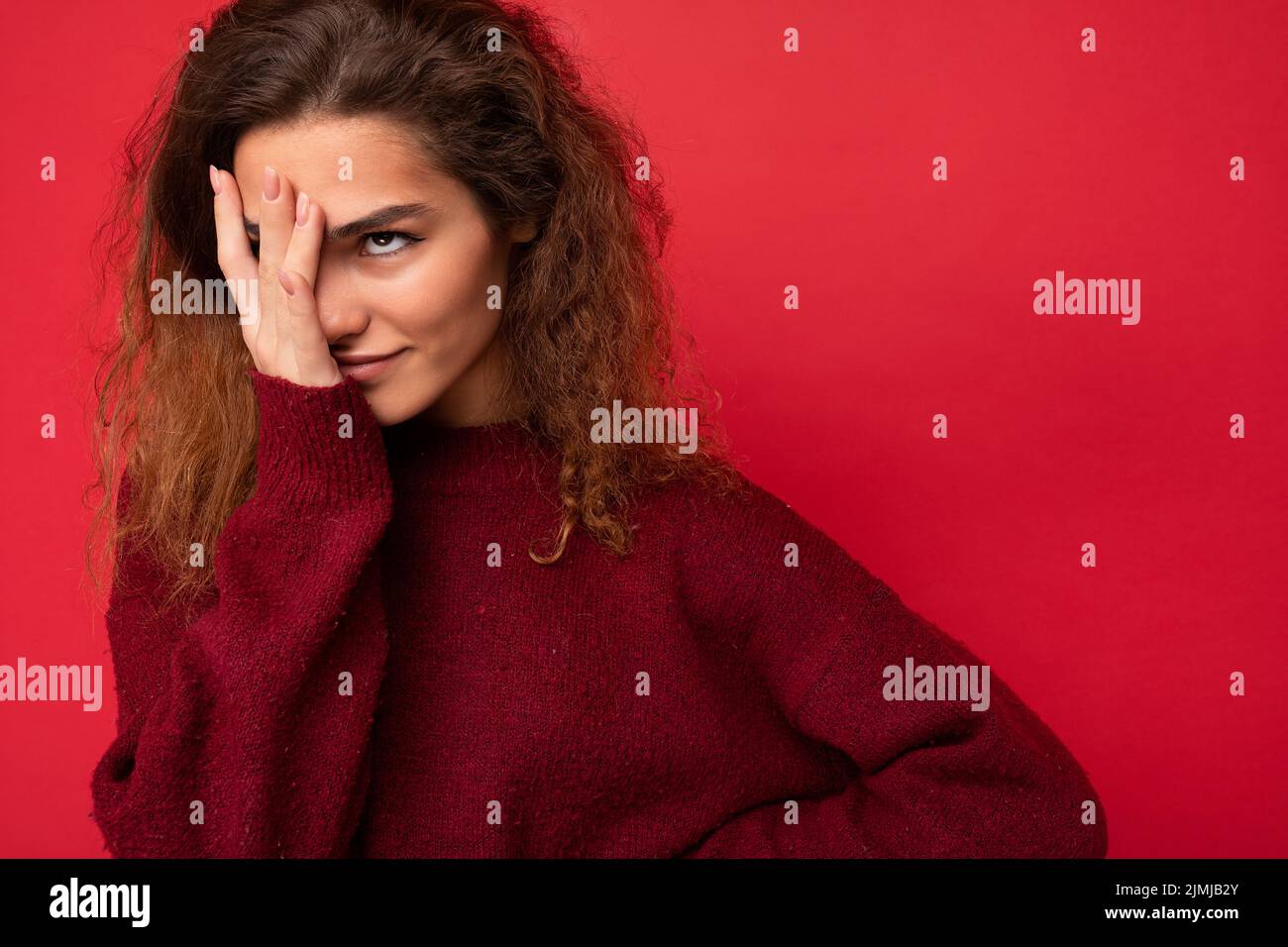 Giovane attraente curly brunette donna con emozioni sincere poising isolato sulla parete di sfondo con copia spazio indossando Foto Stock