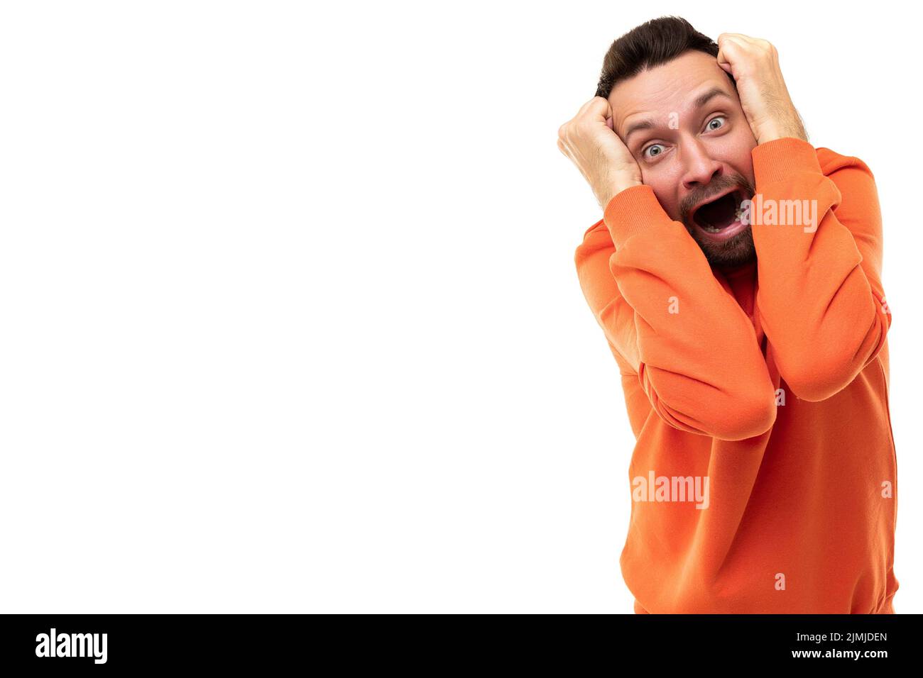 Giovane uomo che tiene la testa con le mani in orrore e paura Foto Stock