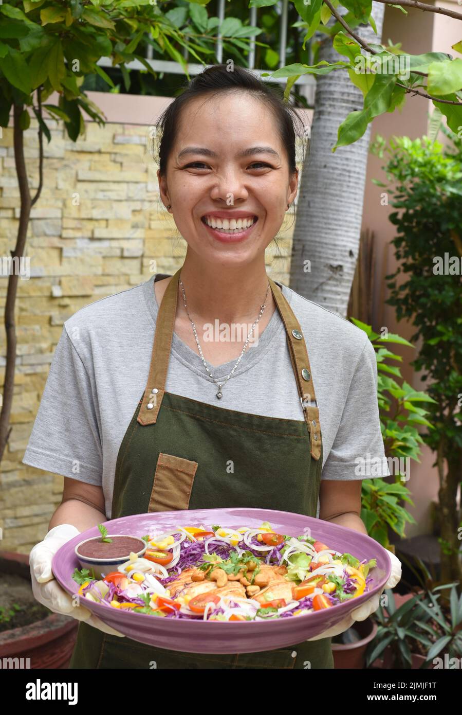 Cameriera vietnamita che serve pollo fritto in padella con verdure in una caffetteria all'aperto Foto Stock