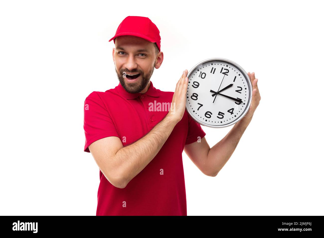 Concetto di consegna rapida in breve, scadenze corriere in uniforme rossa su sfondo bianco con un grande orologio nelle sue mani Foto Stock