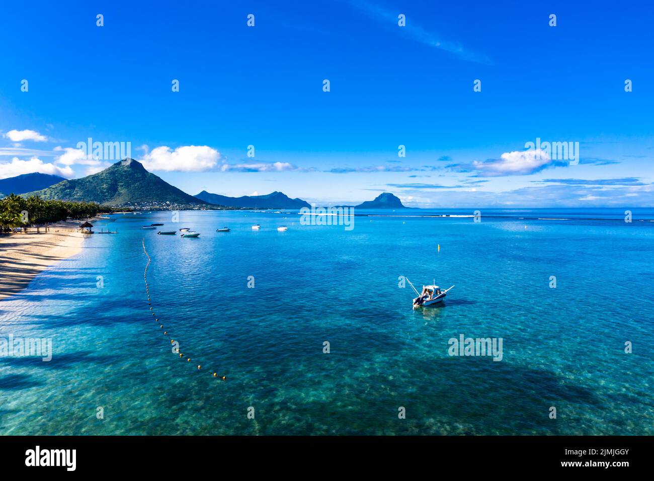 La spiaggia di Flic en Flac con hotel di lusso e palme, dietro la montagna Tourelle du Tamarin, Mauritius, Africa Foto Stock