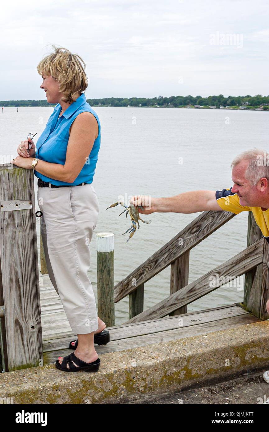 Newport News Virginia, vicino a James River Bridge pesca tempo libero molo d'acqua, granchio donna inconsapevole uomo tenuta catturato Crab umorismo vacanza Foto Stock