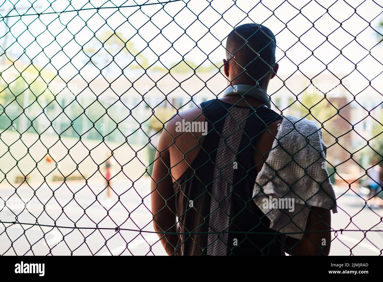 Guarda nello specchio - thats la tua concorrenza. Tiro all'indietro di un giovane sportivo che fa una pausa mentre si trova contro una recinzione su un campo sportivo. Foto Stock