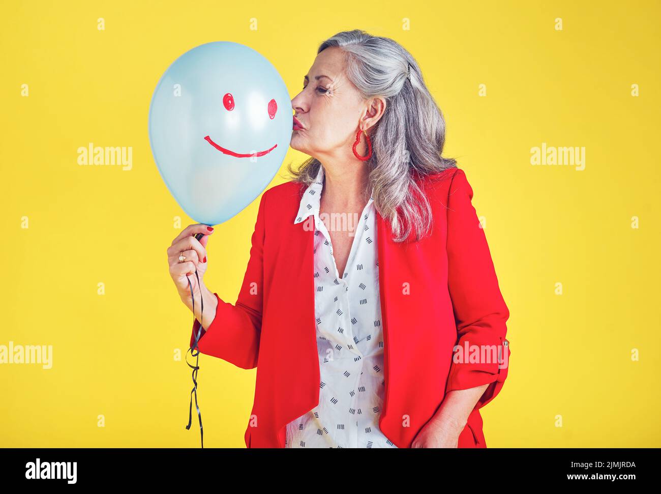Non solo contare i vostri anni, fare i vostri anni contare. Una donna anziana funky ed elegante baciare un pallone su uno sfondo giallo. Foto Stock