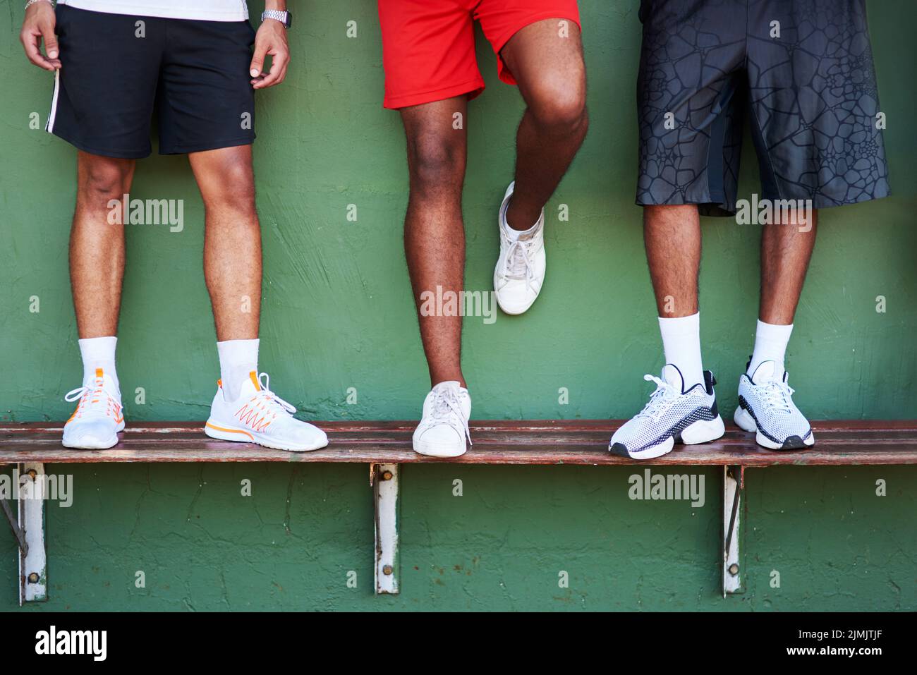 Sei pronto a potenziare il tuo gioco. Primo piano di un gruppo di uomini sportivi in piedi su una panca contro un muro. Foto Stock