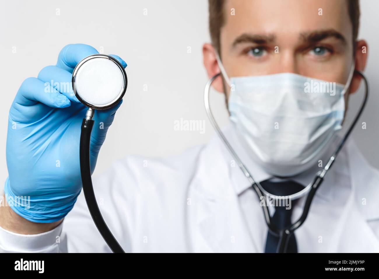 Medico con lo stetoscopio indossare maschera di prevenzione e guanti in lattice Foto Stock