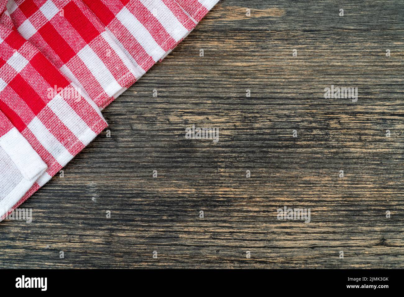 Asciugamano a scacchi rosso sul tavolo da cucina. Sfondo tavola in legno. Foto Stock
