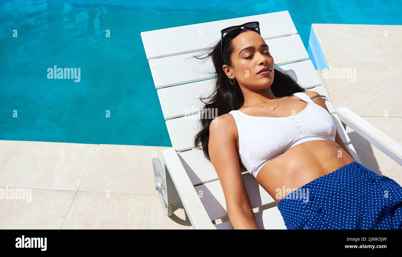 Un po' di tempo al sole è proprio quello di cui ho bisogno: Una bella giovane donna che si rilassa su un lettino a bordo piscina. Foto Stock