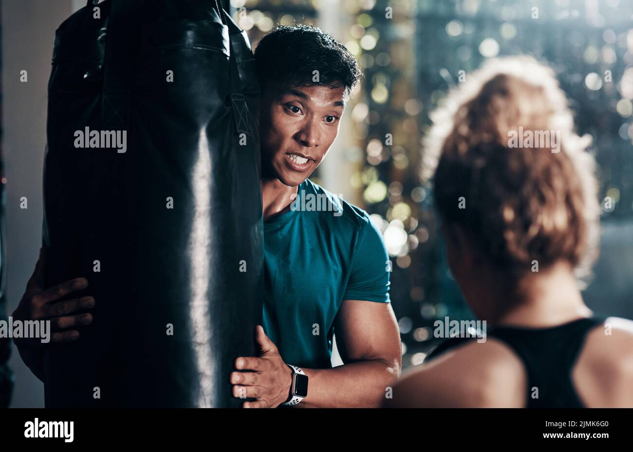 Youre deve assicurarsi che si continua a concentrarsi sulla borsa. Un bel giovane istruttore di fitness maschile istruire un pugile femminile in una palestra. Foto Stock