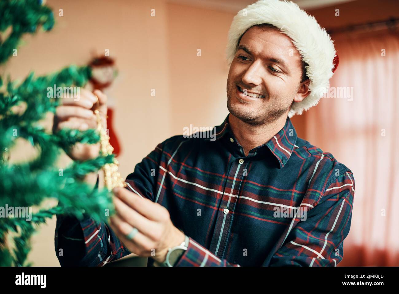 Avete mai visto un albero meglio decorato, un giovane felice che decorava il suo albero di Natale a casa. Foto Stock