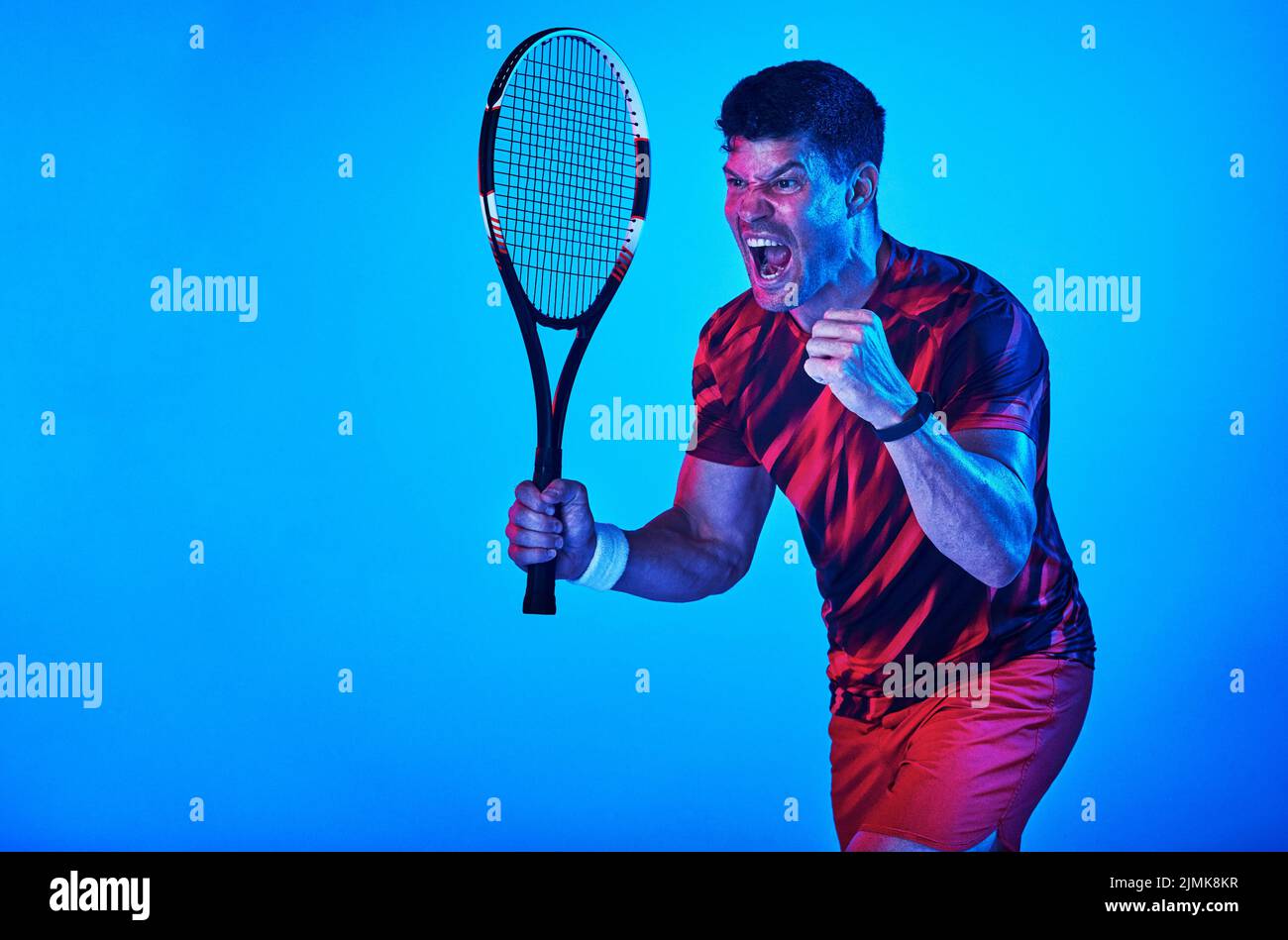 Mi piace questo sport. Scatto blu filtrato di un uomo che posa con una racchetta da tennis in studio. Foto Stock