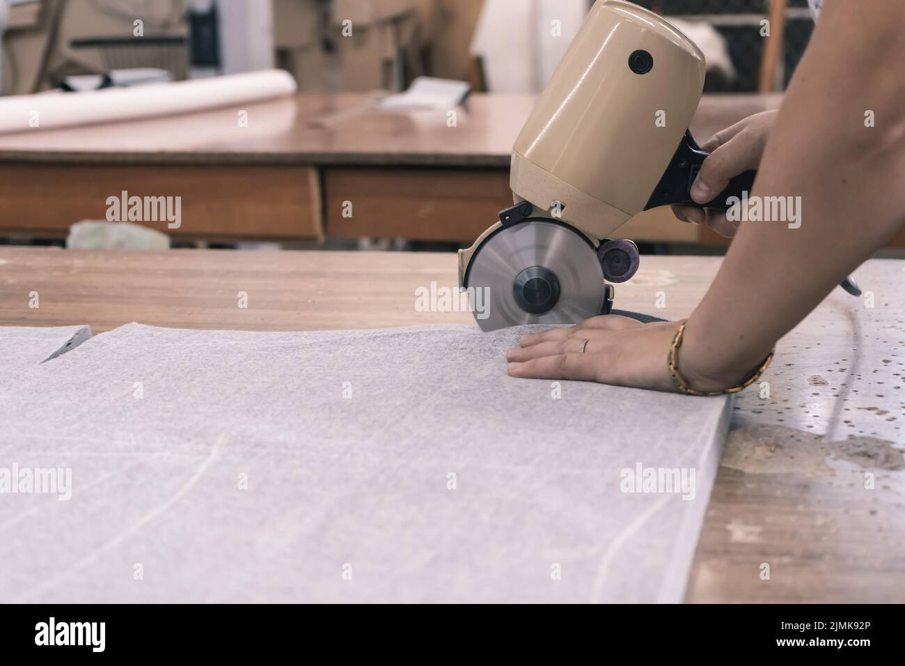 La taglierina taglia il tessuto con un coltello da taglio a disco nell'officina di cucitura Foto Stock