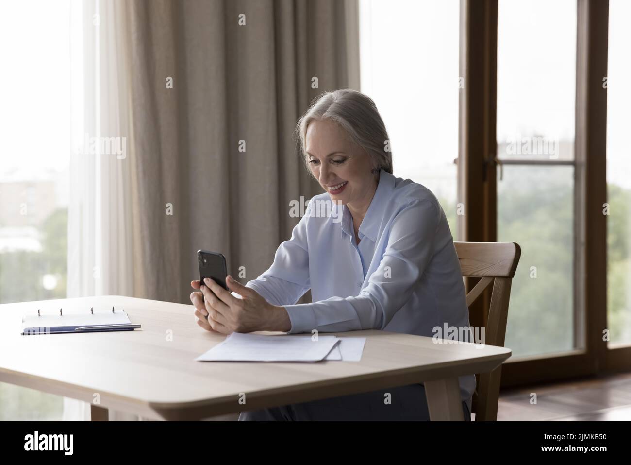 Felice anziano utente di smartphone in pensione parlare in videochiamata Foto Stock