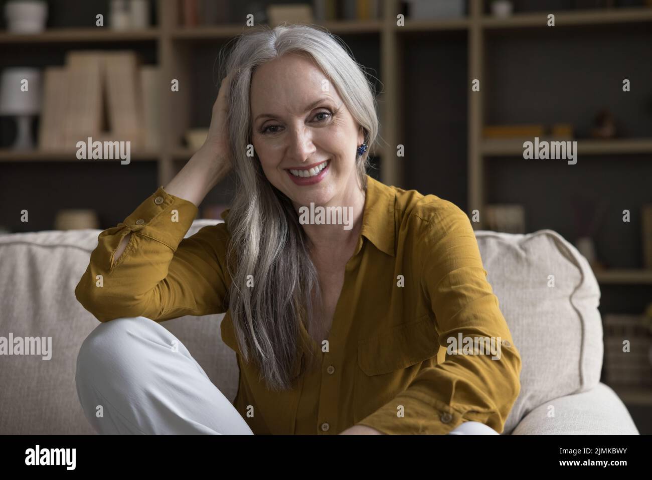 Felice gioiosa più vecchia 50s donna seduta sul divano a casa Foto Stock