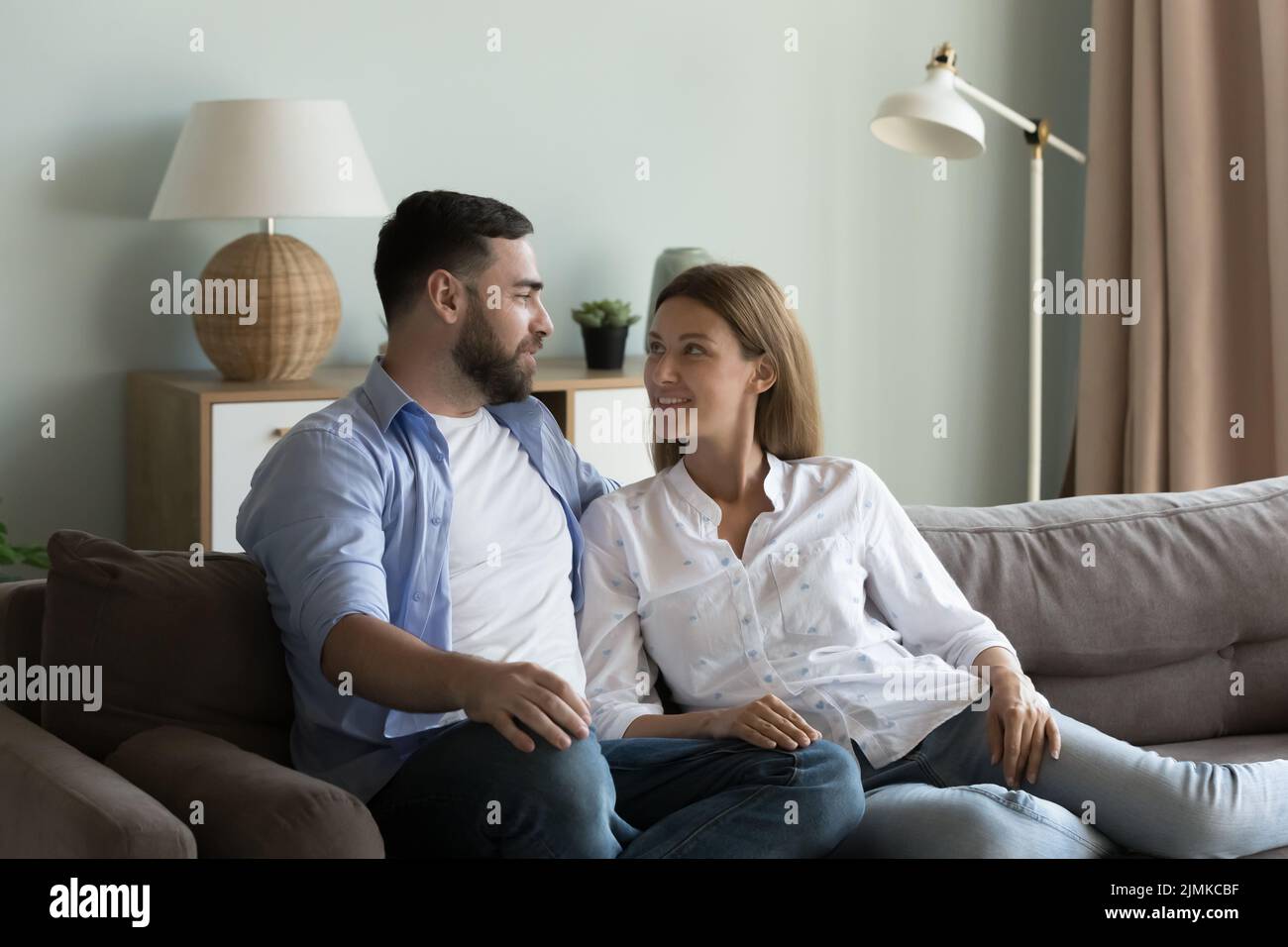 La coppia si rilassa sul divano parlando, goditi il fine settimana a casa Foto Stock