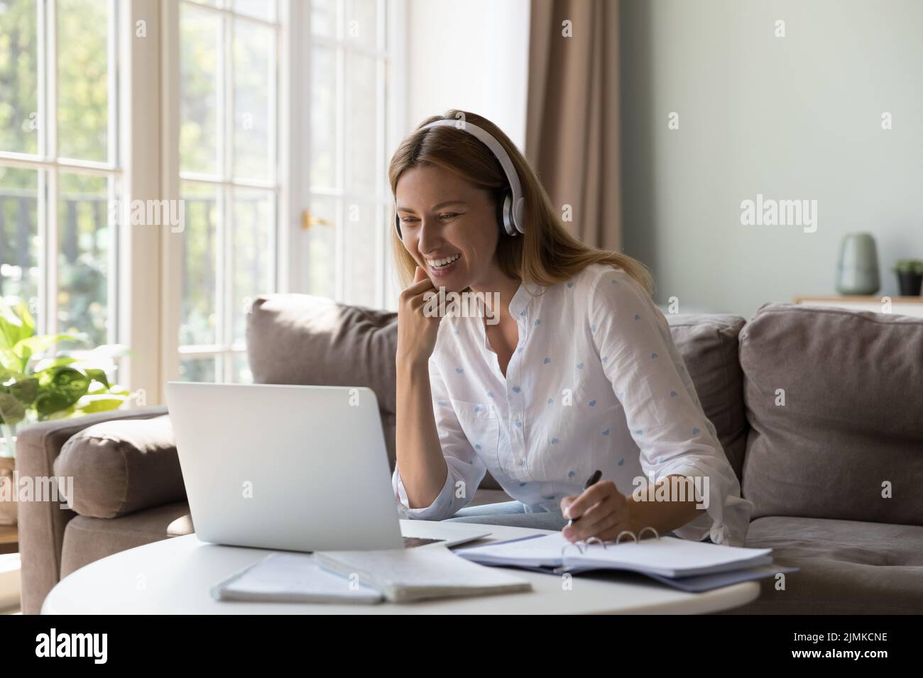 Donna sorridente in cuffie che studia da casa usa l'app Videocall Foto Stock