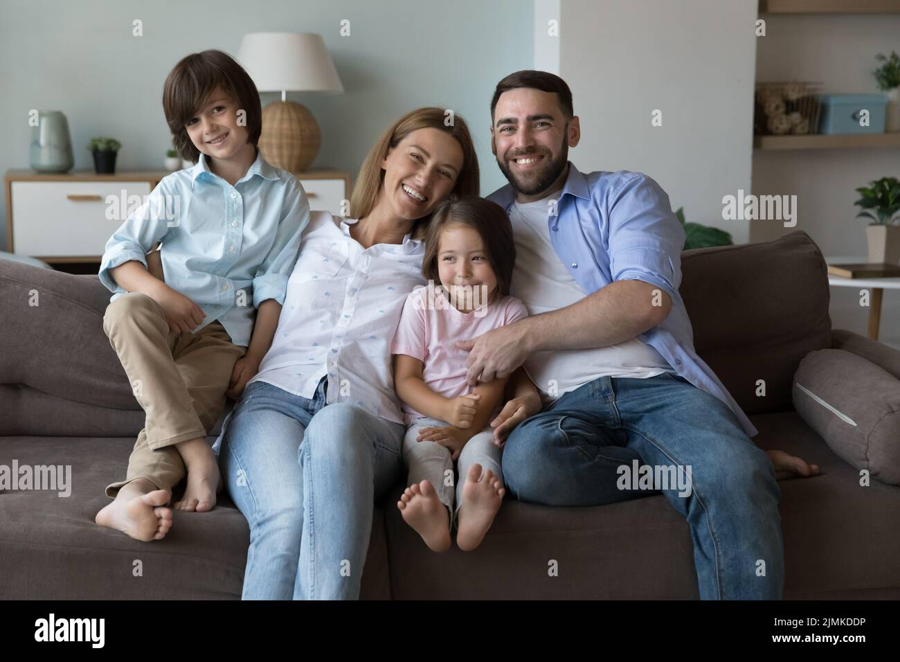 Coppia felice con i bambini che posano per la macchina fotografica seduta sul divano Foto Stock