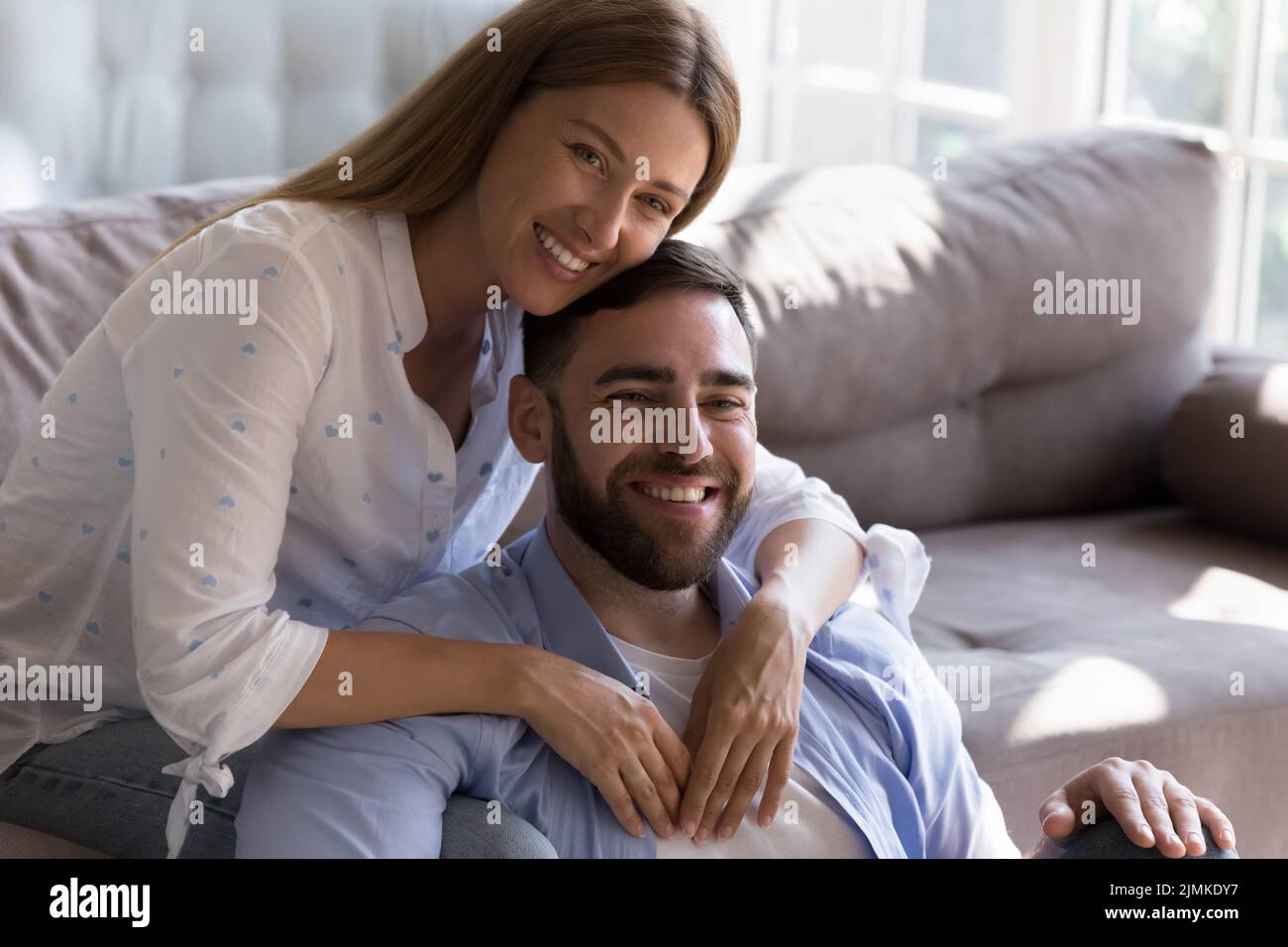 Moglie che abbraccia il marito sorridendo godere il tempo insieme a casa Foto Stock