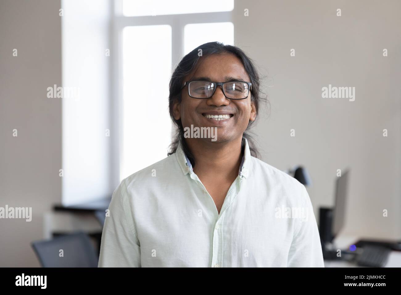 Headshot ritratto sorridente uomo d'affari indiano in posa sul posto di lavoro Foto Stock
