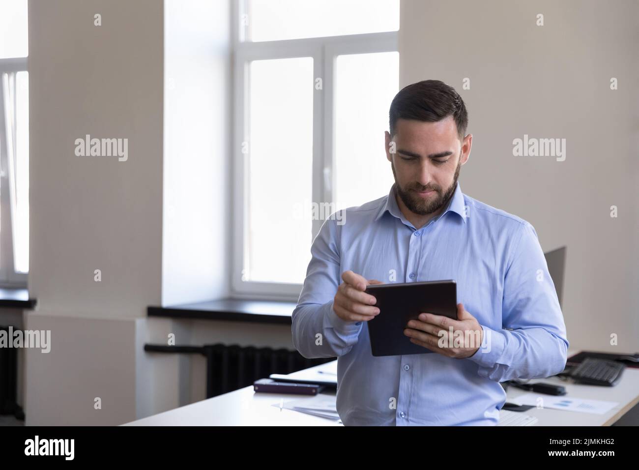 Un uomo d'affari serio, un imprenditore, un impiegato d'ufficio che lavora al tablet digitale Foto Stock