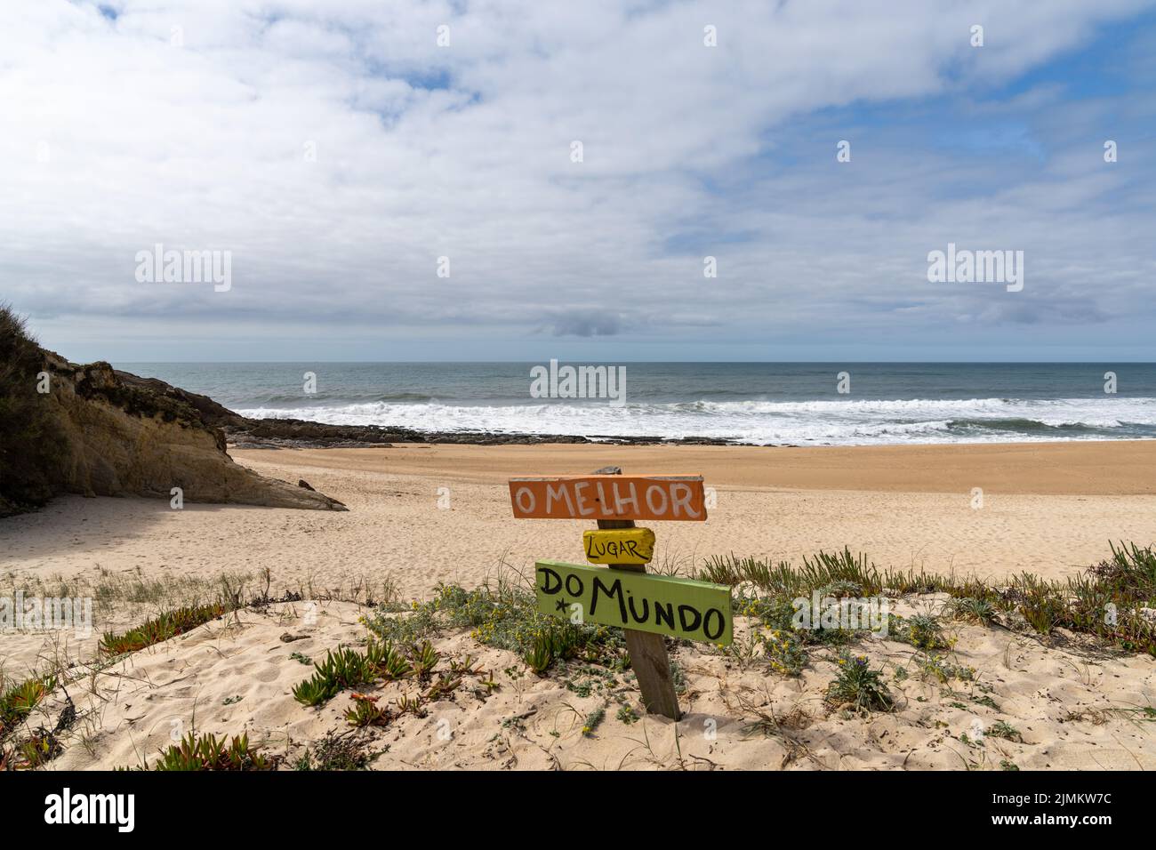 Pittoresca spiaggia vuota con un segno colorato che legge il posto migliore del mondo in portoghese Foto Stock