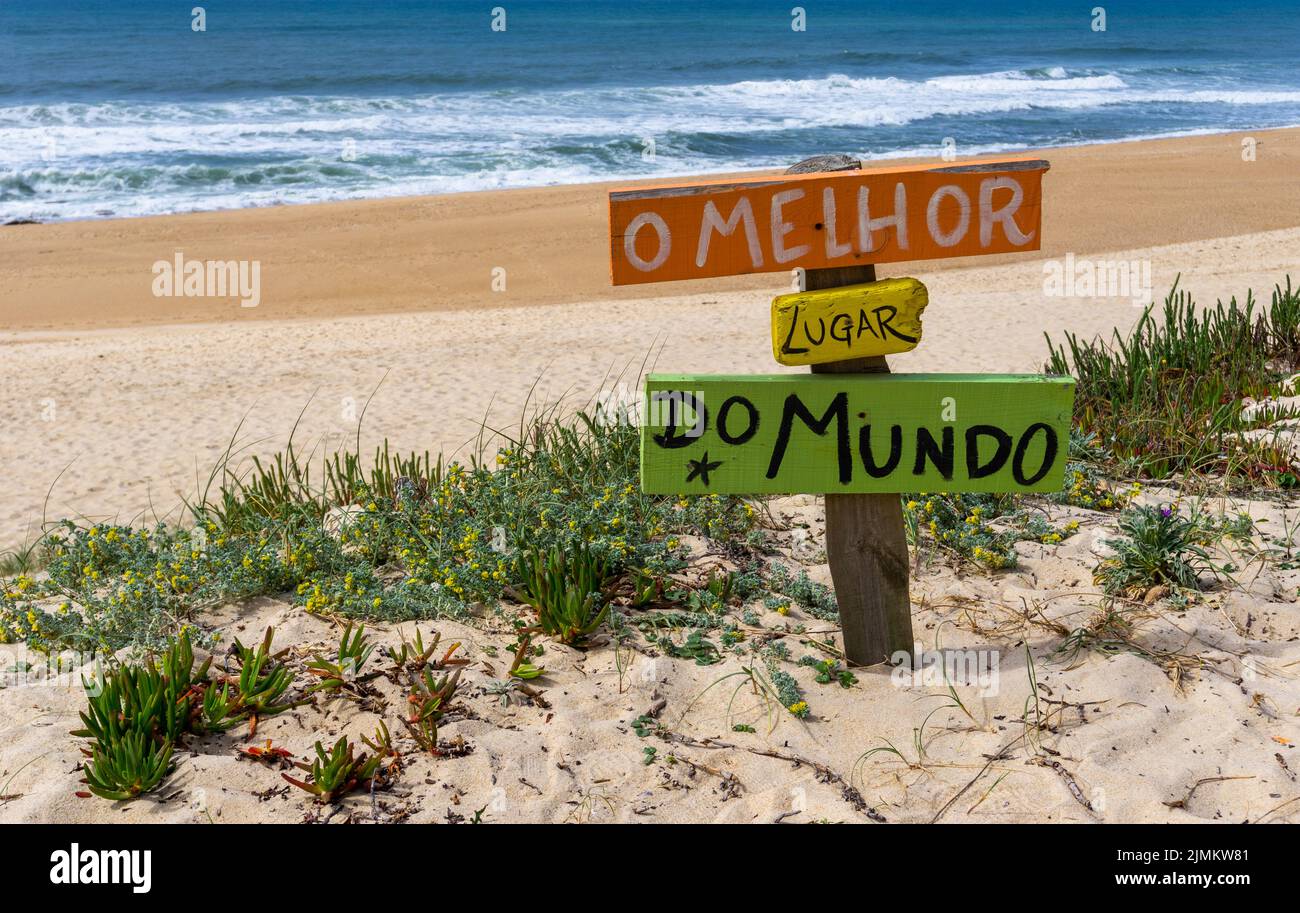 Pittoresca spiaggia vuota con un segno colorato che legge il posto migliore del mondo in portoghese Foto Stock