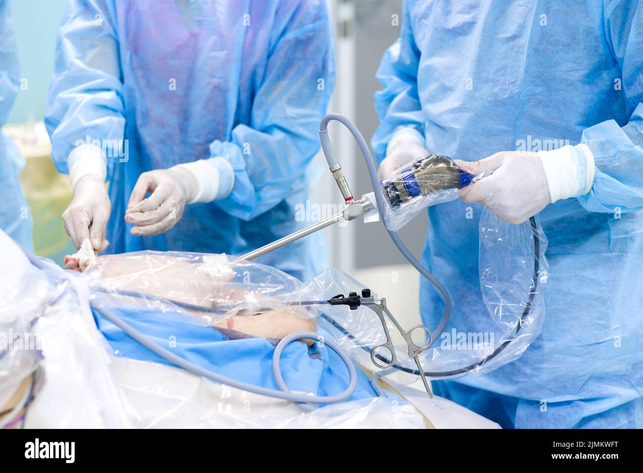 Un team di chirurghi lavora su un paziente su un tavolo operatorio. Foto Stock