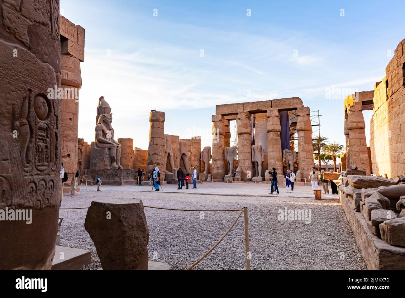 I turisti che camminano nel cortile di Ramses II con un'enorme statua di Ramses II Foto Stock
