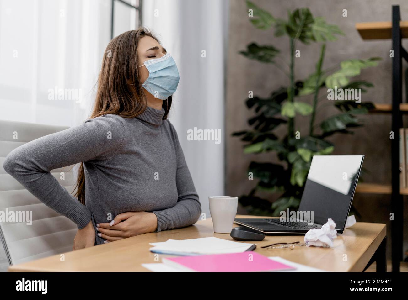 Donna che ha mal di schiena mentre lavora a casa Foto Stock