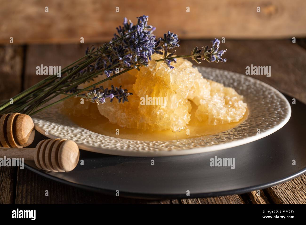 Miele e nido d'ape su un piatto bianco. Cibo dolce in una ciotola sul tavolo. Un prodotto dell'apicoltura. Fiore di lavanda. Foto Stock