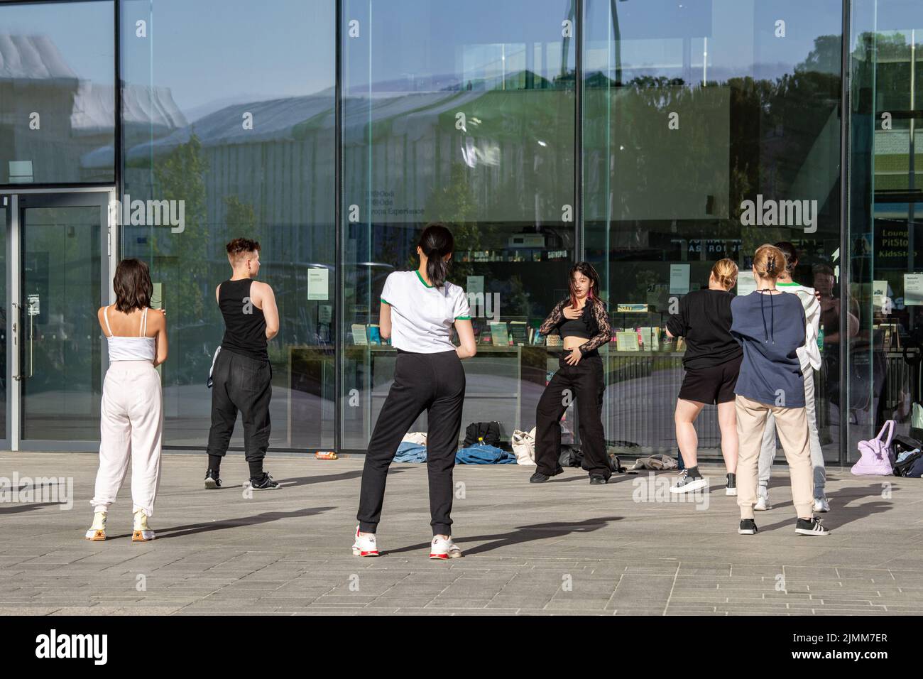 Giovani adulti o adolescenti che praticano la danza si muovono di fronte alla biblioteca di Oodi a Helsinki, Finlandia Foto Stock
