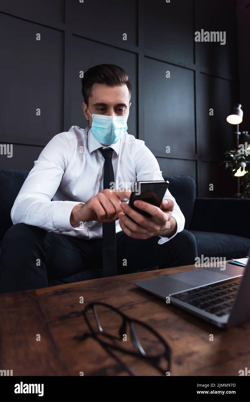 Uomo d'affari che indossa maschera di prevenzione durante il suo lavoro in un ufficio Foto Stock