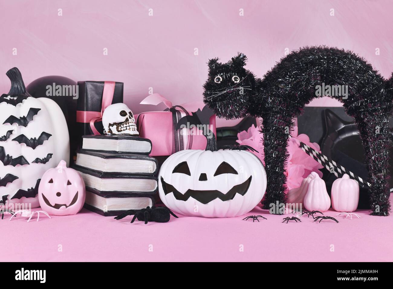 Decorazioni rosa di Halloween con zucche bianche e nere, gatto con libro incantesimo e ragni Foto Stock